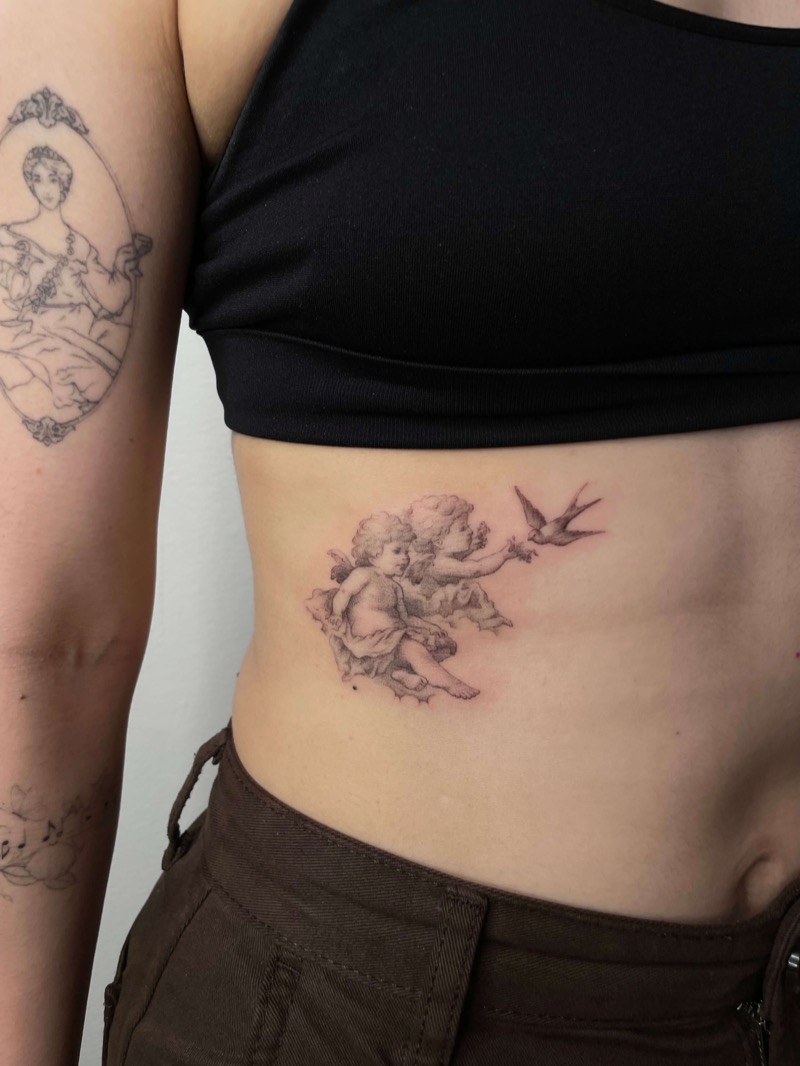 Cherub angel tattoo with bird on ribs by Irka in Helsinki