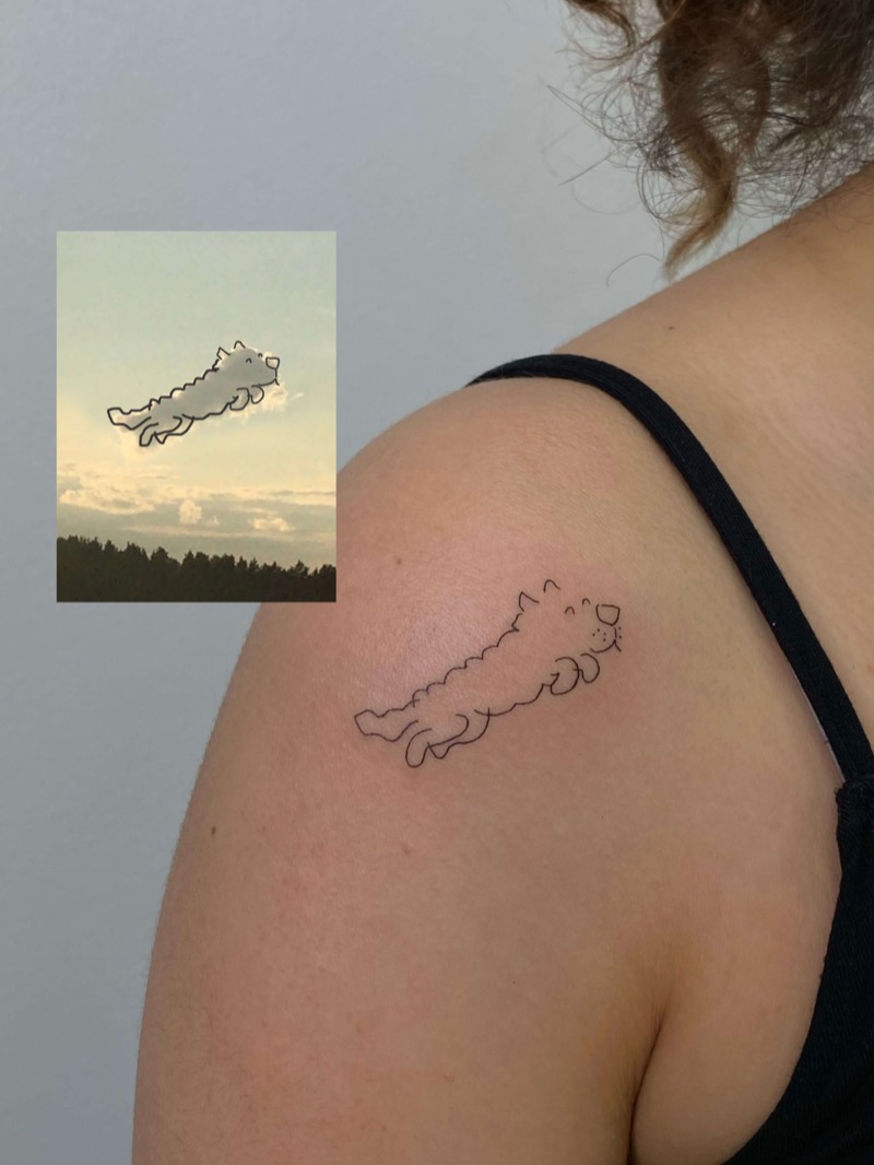Cat-shaped cloud outline tattoo on shoulder by Irka in Helsinki