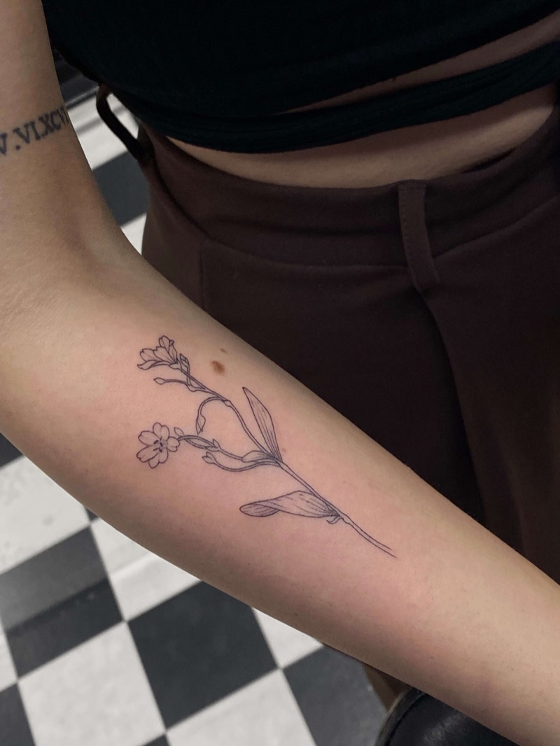 Delicate wildflower branch tattoo on inner arm by Irka in Helsinki